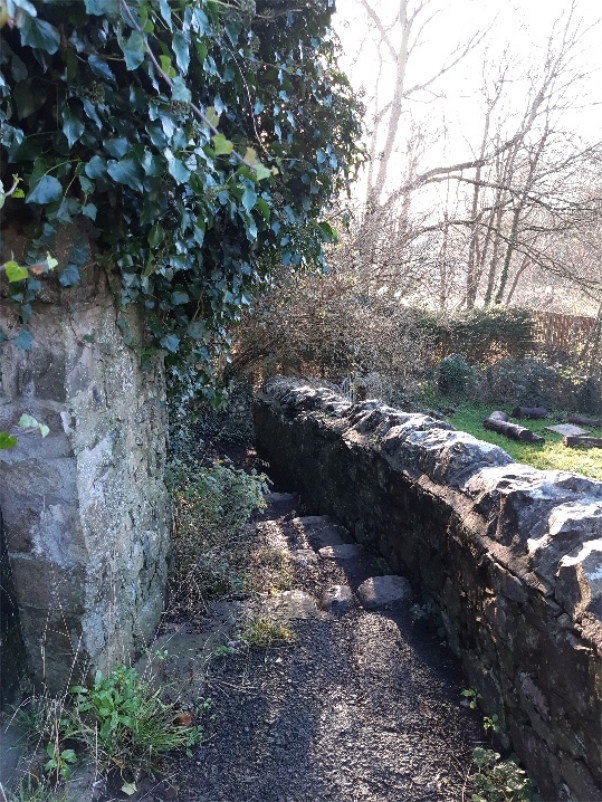 SpiderWebLane with a wall on the right and a building onm the left